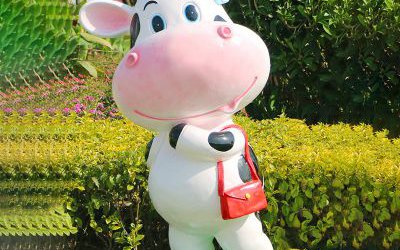 花園里一只拿包的玻璃鋼彩繪卡通仿真動物牛雕塑