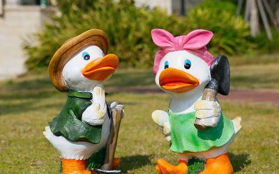 草地上手拿鋤頭和抗鏟子的兩只玻璃鋼彩繪鴨子雕塑